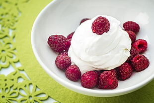 raspberries with whip cream on white bowl