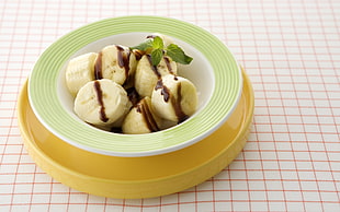 sliced banana with chocolate on white and green ceramic bowl