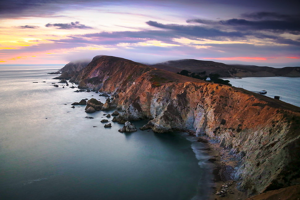 brown sea cliff during dusk photography HD wallpaper