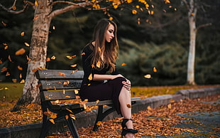 photo of woman sitting on brown bench