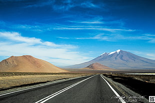 road beside a mountain under blue sky HD wallpaper