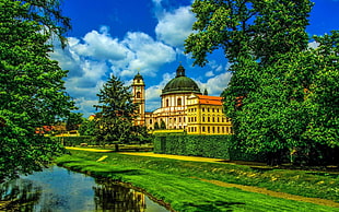 yellow and green mansion near body of water with garden