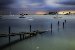 long exposure photograph of wooden dock and boats on body of water