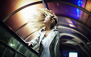 blonde haired woman on gray robe standing on escalator