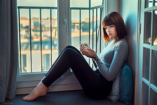 woman in gray long-sleeved shirt sitting near the window