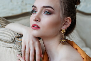woman in orange dress with makeup leaning on sofa