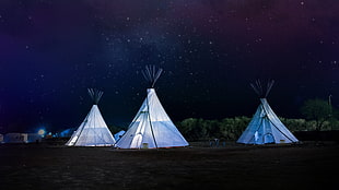 long exposure photograph of three white teepee tents