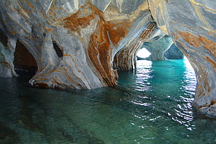 gray and orange cave in large body of water