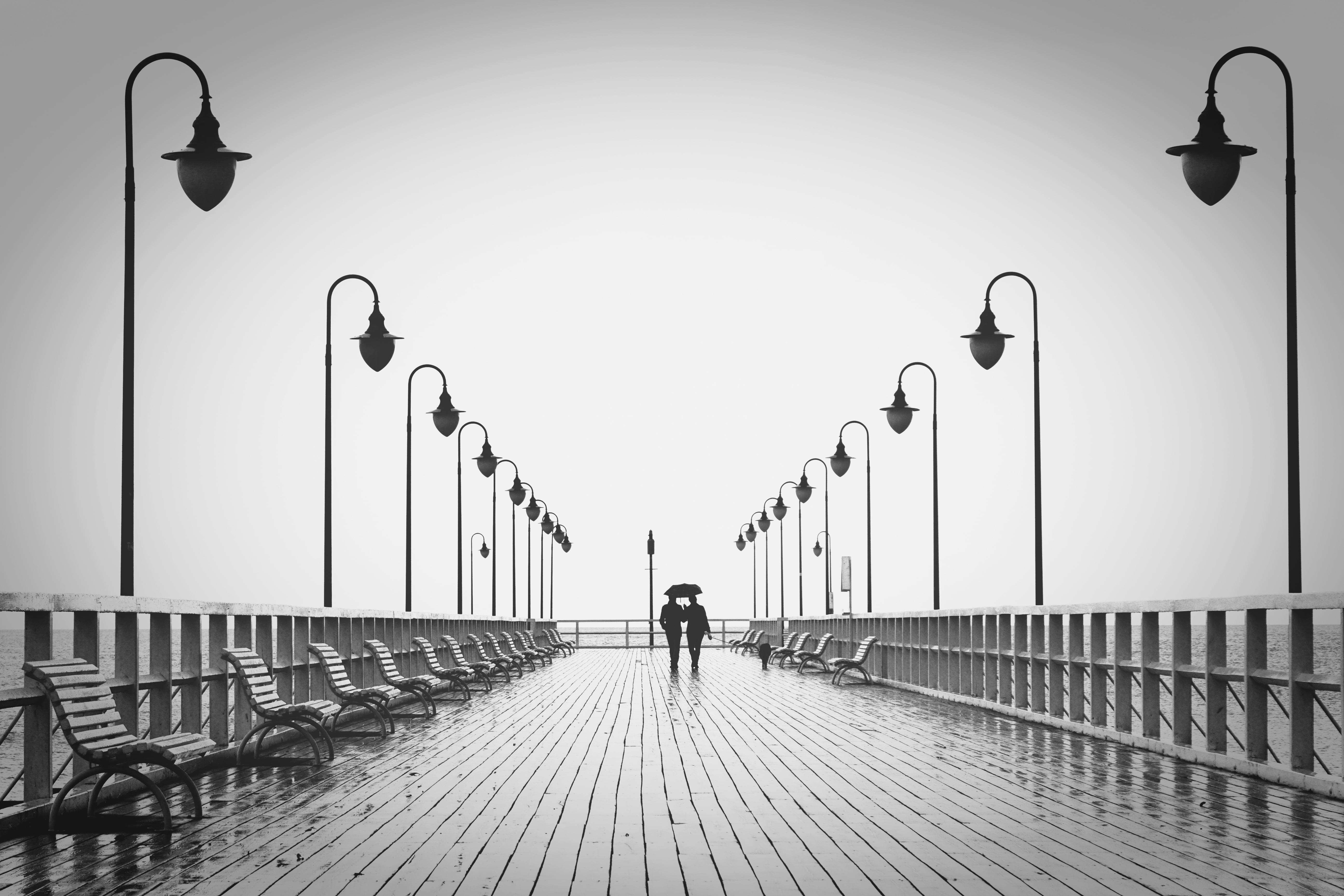 gray scale photo of two person holding umbrella