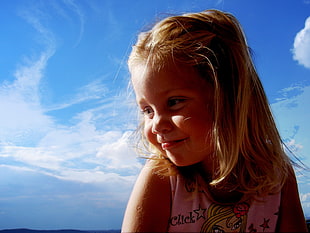 blonde haired girl in pink tank top under blue cloudy sky during daytime