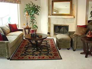 black hardbound book on top of round brown wooden coffee table next to beige 2-seat sofa and ottoman