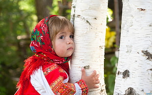 girl wearing red scarf hugging tree