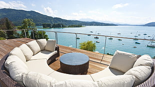 white corner sofa set with brown wicker frame facing body of water full of boats during daytime