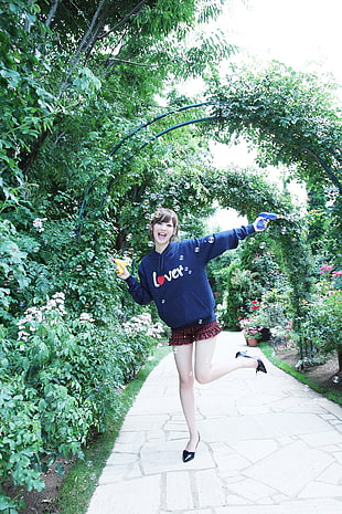 woman wearing blue hoodie standing between the plants during daytime