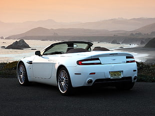 white convertible coupe on seaside under cloudy sky during daytime HD wallpaper