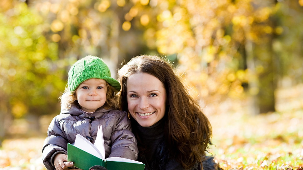 selective focus photography of woman sitting beside girl holding book HD wallpaper