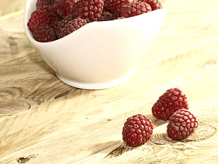red fruits in white ceramic bowl