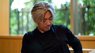 man sitting wearing black dress shirt near glass window