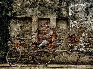 bicycle parked beside gray concrete wall