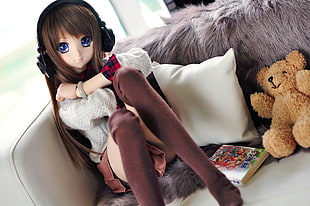 anime girl life-size action figure siting in sofa beside brown bear plush toy