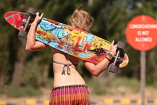 woman holding red and yellow longboard