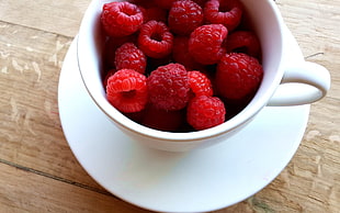 white ceramic cup and saucer with red raspberry fruits