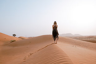 woman in black and brown maxi dress walking on desert HD wallpaper