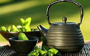 brown ceramic tea pot and ceramic bowl with mint leaves