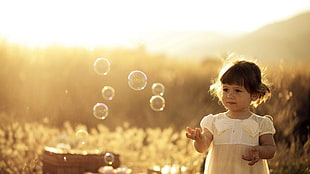 girl in white dress playing bubble during sunset