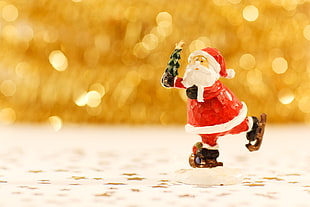 selective focus, macro, and bokeh photography of Santa Claus  holding tree with star figurine on white surface