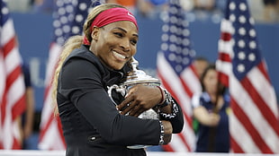 woman in black jacket hugging the silver-colored trophy