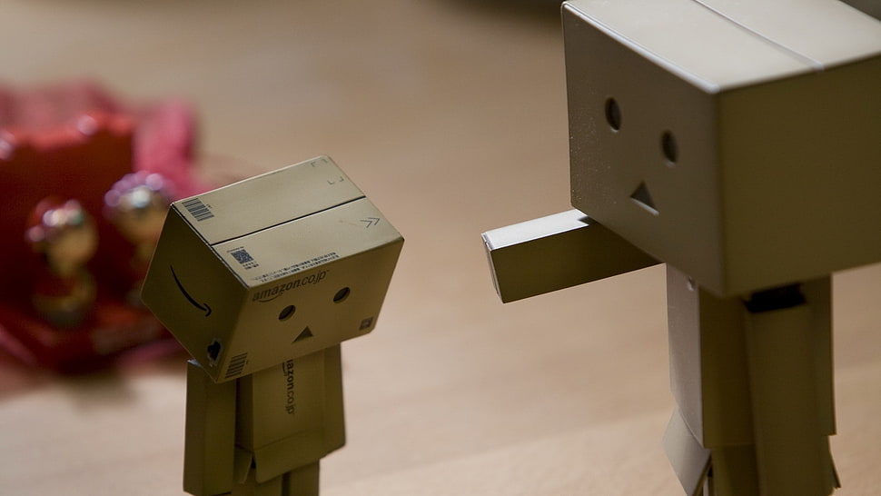 depth of field photo of two DIY box human figures on top of brown wooden table HD wallpaper