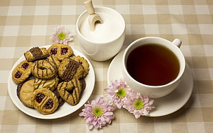 white ceramic teacup and brown cookies on white ceramic plates