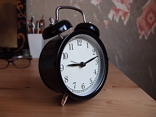 turned-on alarm clock on brown wooden table