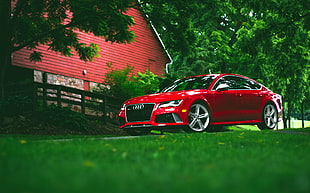 red Audi sedan parked near red house