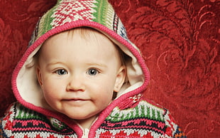 black haired baby in red, green and black knit jacket
