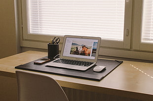 Macbook Air turned beside apple magic mouse on brown wooden table