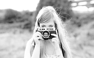 selective focus grayscale photography of woman holding SLR camera