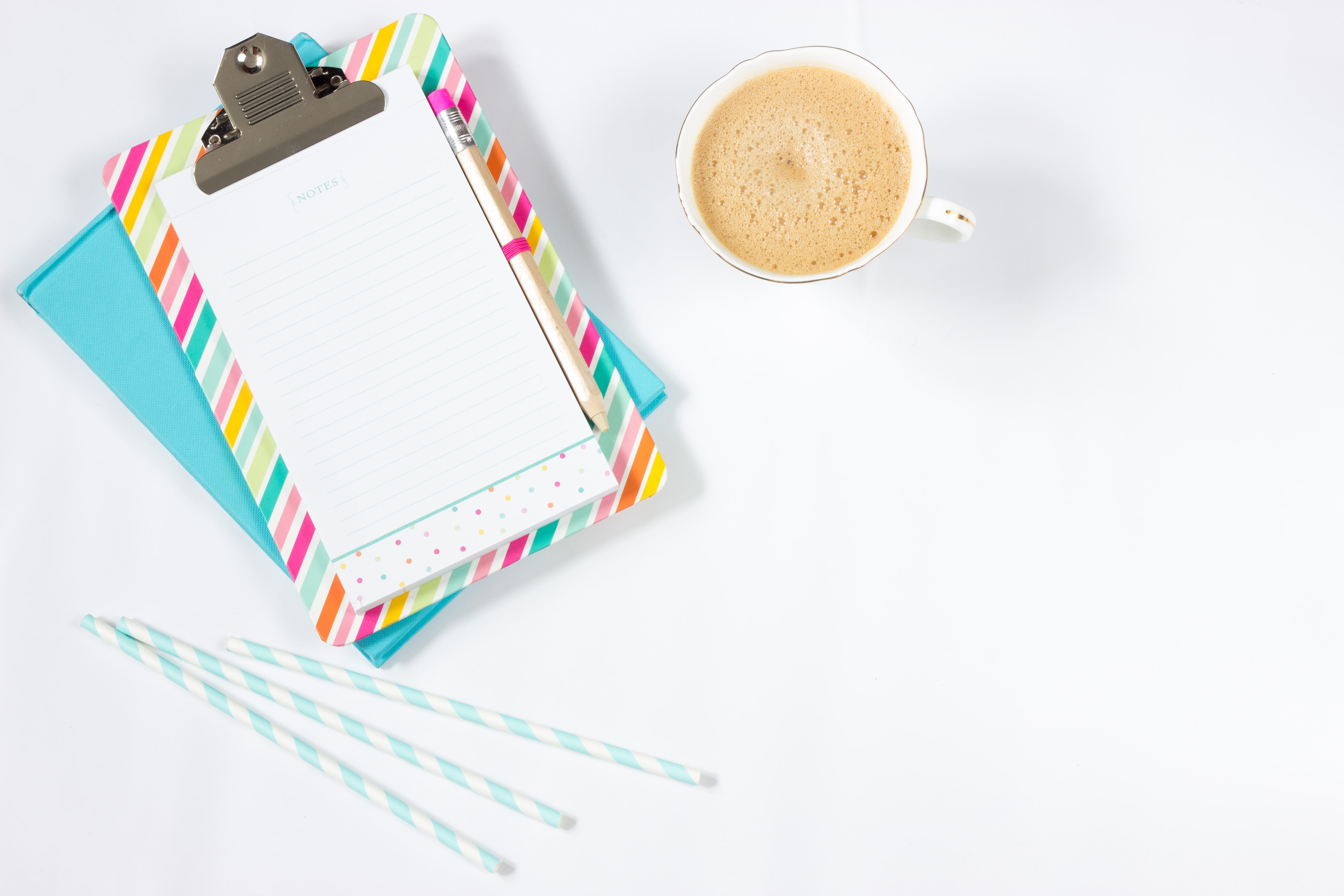 white ceramic mug filled with coffee beside white clipboard