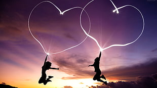two persons jumping on air holding heart-shaped LED lights HD wallpaper
