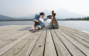 couple on wooden dock near body of water HD wallpaper