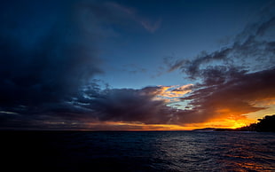 body of water under orange sunset