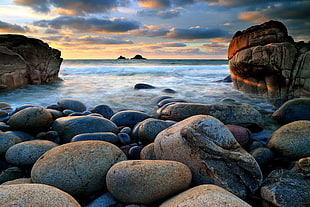 gray and brown stones beside body of water during sunset HD wallpaper