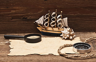 magnifying glass beside sailing ship miniature on table