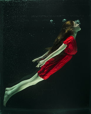 woman in red elastic waist dress under water