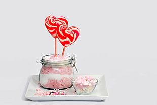 red-and-white candy hearts on a stick on clear glass jar with white-and-pink sand HD wallpaper