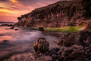 seashore near cliffs during golden hour HD wallpaper