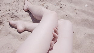 person legs lying on gray sand taken during daytime
