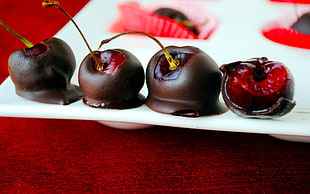 four red berries coated chocolate with white plate