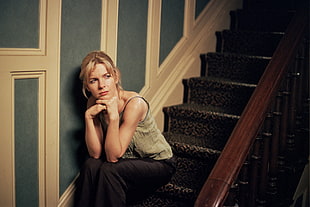 woman in gray sleeveless top and black pants sitting on stairs